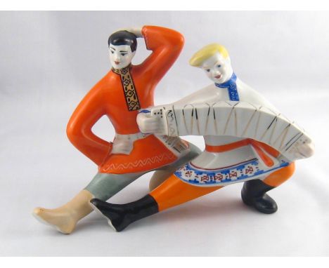 A Russian ceramic group of two Cossack dancers, one playing a piano accordion. Length 26cm . 