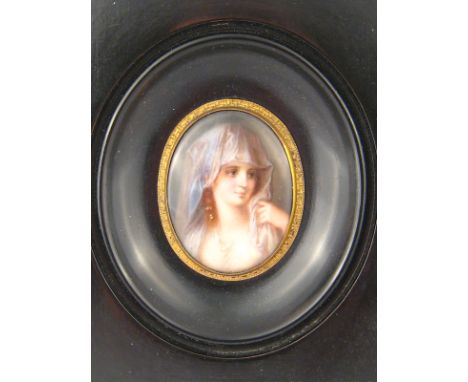 A hand painted portrait miniature on porcelain, mounted as a brooch and set in a wooden frame, miniature approx 42 x 35mm.