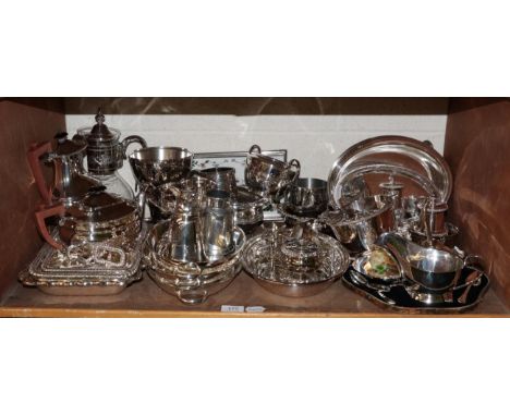 A shelf of silver plated items including a tea set, stirrup cup, entree dishes and covers, claret jug, etc