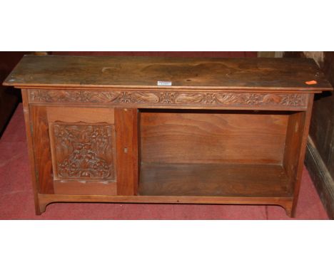 An early 20th century walnut relief carved hanging wall shelf, having single cupboard door and open compartment, width 74cm