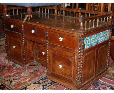 An Aesthetic Movement joined oak and elm kneehole writing desk, having three quarter raised gallery with spindle brass turnin
