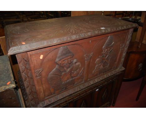 An early 20th century Continental raised and relief carved walnut hinge top blanket box, the front panel decorated with music