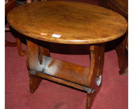 An oak oval low occasional table having book trough undertier