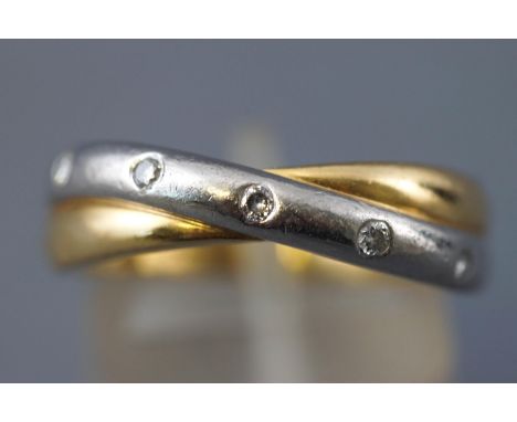 A yellow and white metal crossover ring. Flush set with five round brilliant cut diamonds, stamped total weight of 0.10cts. h