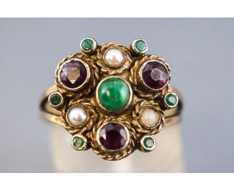 A yellow metal dress ring.  Centrally set with a cabochon cut emerald and finished with faceted cut rubies and emeralds toget