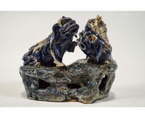 A 19th century Chinese earthenware figure of two Dogs of Fo playing on a rocky base, all over glazed in blues and cream, and 