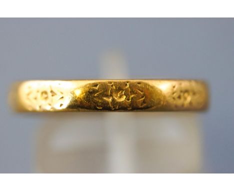 A yellow metal court shaped wedding ring with engraved design. Hallmarked 22ct gold, London. Size: O 5.5 grams