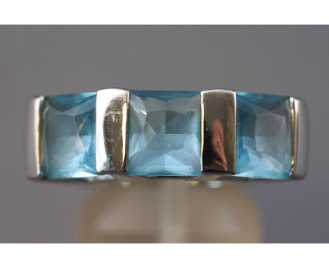 A rhodium plated three stone ring by Swarovski. Set with three square faceted cut blue crystals. Supplied with original box a