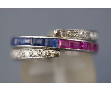 A white metal 'night and day' ring set half and half to central band with square cut sapphires and rubies. Additionally havin