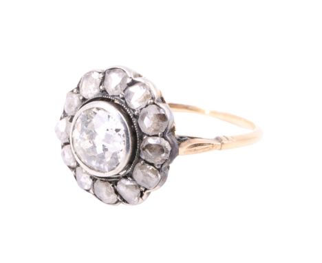 A vintage diamond cluster ring, having an 0.8 ct brilliant bezel set and surrounded by 12 old cut diamonds (approximately 0.5