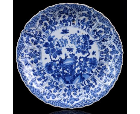 Porcelain dish with contoured rim and blue and white decor of butterflies in flower garden and richly decorated rim of flower