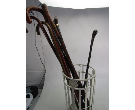 Collection of vintage walking sticks in metal stick stand 