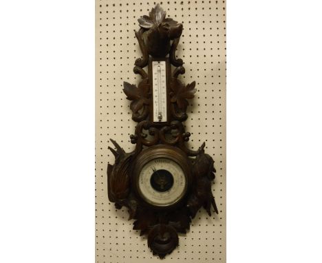 A Black Forest type carved wooden framed barometer / thermometer, the barometer and thermometer French, the frame carved with
