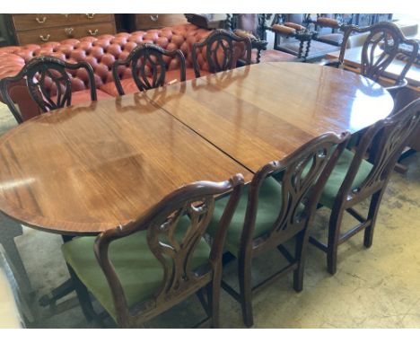 A set of seven George III style mahogany dining chairs (one with arms) together with a mahogany twin pillar extending dining 