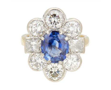 A sapphire and diamond cluster ring claw set with an oval mixed-cut sapphire, a square mixed-cut diamond to each side, and si