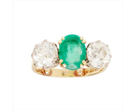 An emerald and diamond set three stone ring claw set with an oval shaped emerald, flanked to either side by an old round-cut 