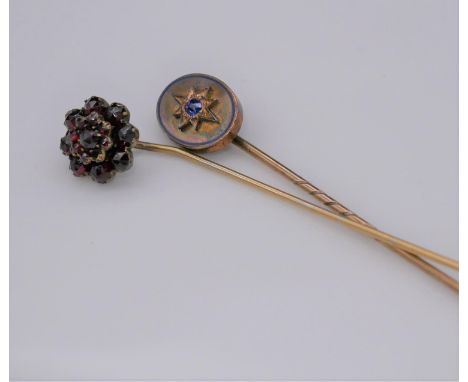 Two antique gemset stick pins. One oval yellow metal pin set to centre with a cushion shape Ceylon sapphire with an approxima