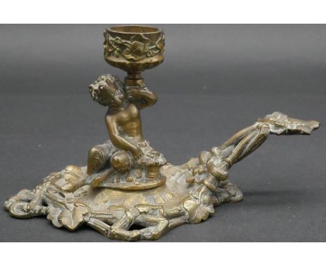 A C.1900 cast brass chamber stick of cast young faun holding a flower with basket at his feet, the base and handle sculpted a