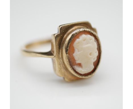 A 9ct yellow gold and shell cameo ring, with carved cameo of a lady in side profile in a square bezel. Flowing down to trumpe