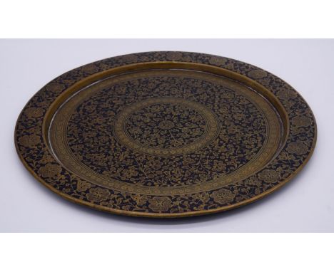 An antique Indian brass and black enamel platter. Engraved with a stylised floral and foliate design. D.38cm 