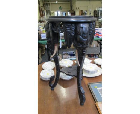 A Far Eastern ebonised jardiniere stand, with elongated elephant mask and trunk supports