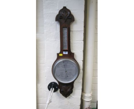 An Edwardian oak wheel barometer, the thermometer to neck and primary silvered dial between leafy mouldings, 81 cm