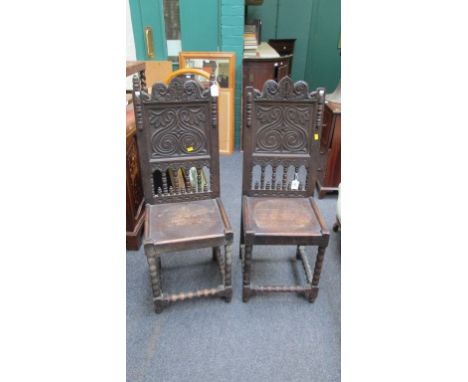 A pair of 17th century style carved and turned oak back stools, with shaped cresting rails above captive panel seats, raised 