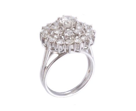 A 1970s diamond cluster ring, the central brilliant cut diamond, estimated to weigh 0.70 carats, claw set within a surround o