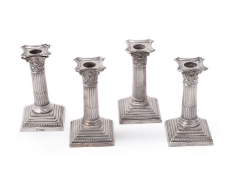 Four late Victorian silver Corinthian candlesticks by William Hutton & Sons Ltd., London 1900 (3) and Sheffield 1900 (1), the