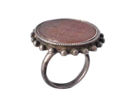 An early 20th century cornelian and silver ring, possibly Persian or Turkish, the circular cornelian plaque intaglio engraved