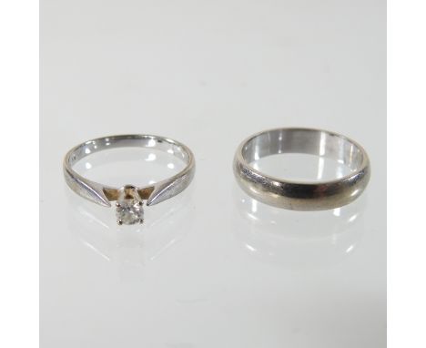 An 18 carat white gold wedding band, 3.6g, size K, together with a 9 carat gold solitaire diamond ring, 1.8g, size K, boxed (