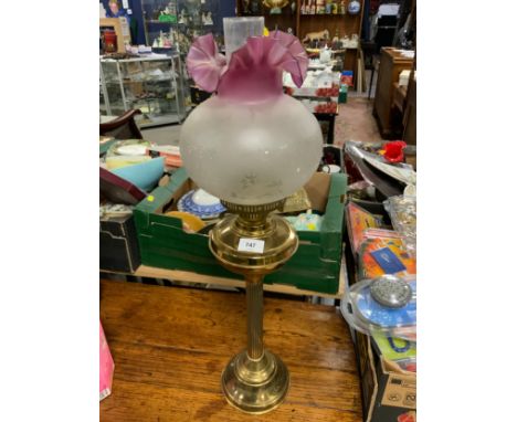 A brass Corinthian column oil lamp with ruby edged shade 