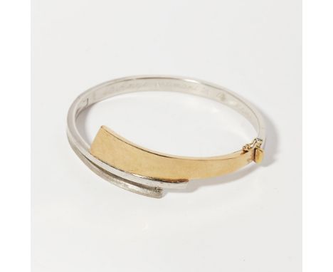 A modern bi-coloured hinged bangleof tapering asymmetric cross over design, unmarkedInternal diameter: 57mm