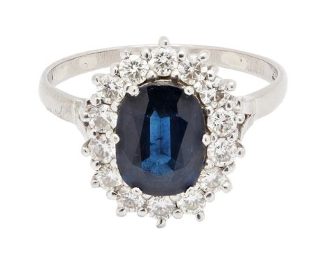 A sapphire and diamond set cluster ringclaw set with an oval-cut sapphire, in a border of round brilliant-cut diamonds, to a 