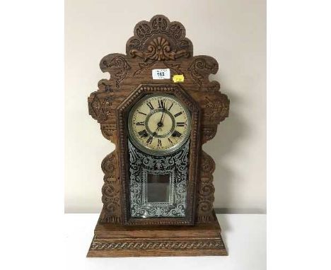 An antique carved American mantel clock with pendulum and key