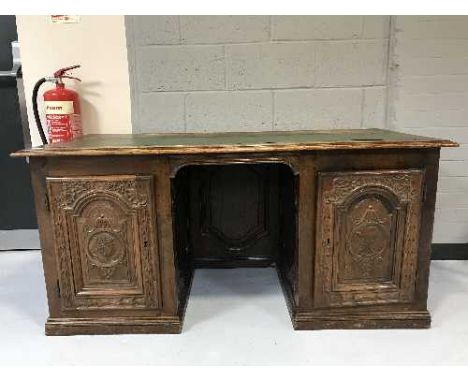 An antique oak and mahogany twin pedestal desk with carved panel doors inset green leather panel 