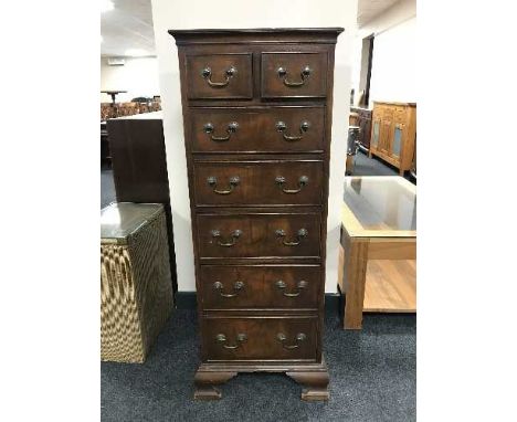 A walnut seven-drawer chest with brass drop handles on bracket feet