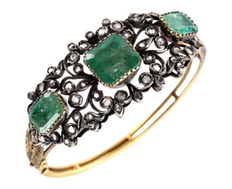 A fine Victorian emerald and diamond hinged bangle, unmarked gold and silver-topped openwork settings with three emerald-cut 