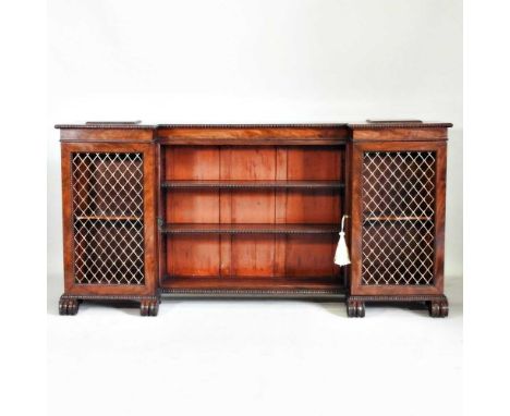 A Regency mahogany inverted breakfront sideboard, with spindle moulding, enclosed by metal grille doors, on scrolled feet, to