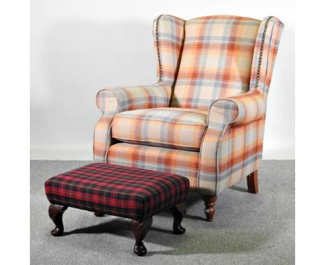 A modern tartan upholstered wing armchair, on turned legs, together with a footstool (2)