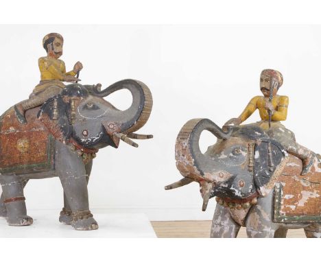 A pair of Rajasthani carved and painted wooden elephants, first half of the 19th century, Indian, each with a mahout rider, t