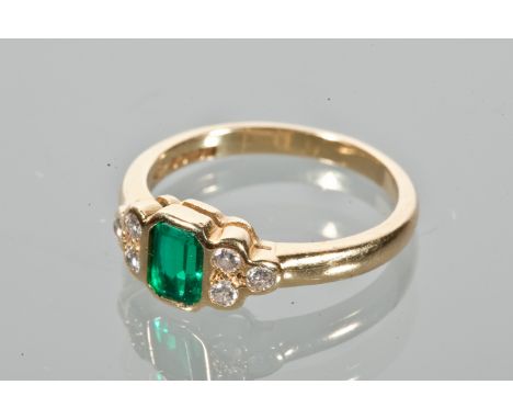 EMERALD AND DIAMOND RING
set with a central emerald cut emerald flanked by two groups of three diamonds, in eighteen carat go