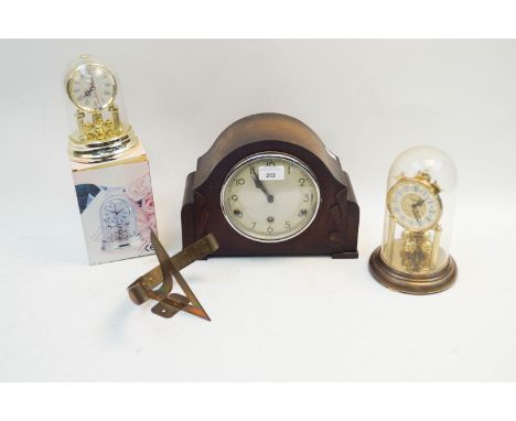 A wooden mantle clock with two others and a brass sundial