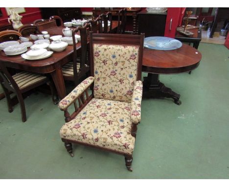 An Arts &amp; Crafts walnut armchair on turned legs and ceramic castors