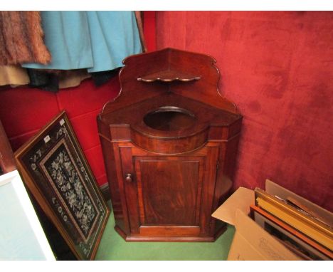 An early Victorian flame mahogany corner washstand, the raised back over a ceramic wash bowl insert and single door cupboard,