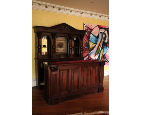 A fine carved mahogany Bar and Counter, with arched and carved cornice above a centre leaded and stained glass panel and flan