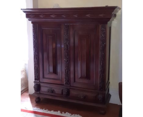 A 17th Century style walnut Armoire with moulded cornice above two moulded and carved cushion panel doors flanked with vine c