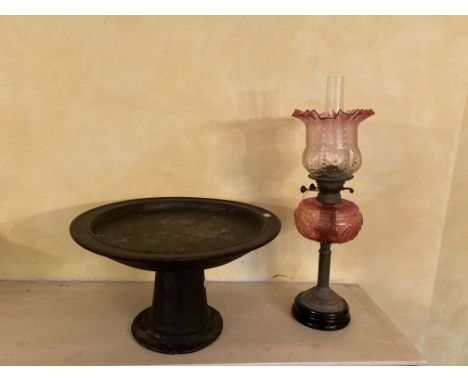 An Edwardian brass and ruby glass Oil Lamp, with shade and a circular African Tribal stemmed stand, 20'' (51cms). (1) 