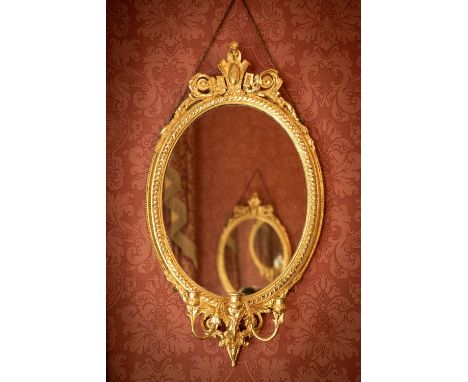 A very attractive pair of 19th Century gilt Girandoles, each with a cartouche crest and leaf scrolls above an oval mirror pla