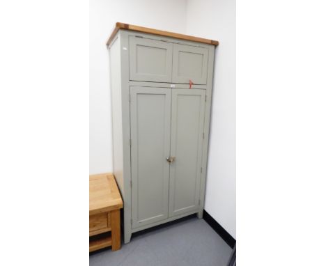 A modern painted kitchen pantry unit with double doors opening to reveal shelves, drawers and bottle rack with spice shelves 
